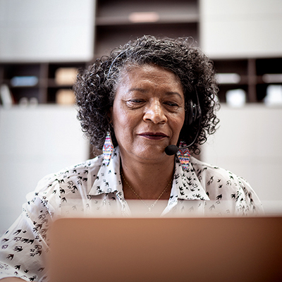A woman with a headset on, looking at a desktop