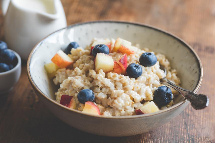 A bowl of oatmeal with blueberries and apples