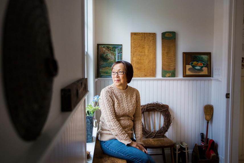 A senior woman sits by a window