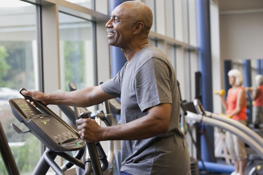 An elder uses a stair machine at a gym