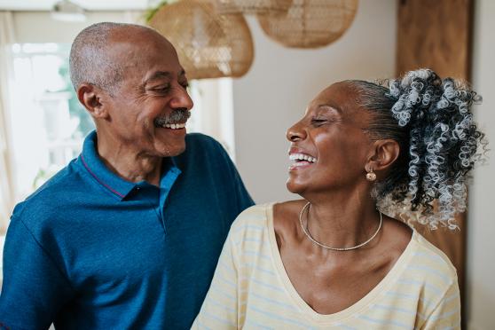 An elderly couple laughs and looks at each other