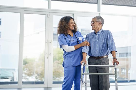 A nurse helps a senior patient with a walker at a medical facility