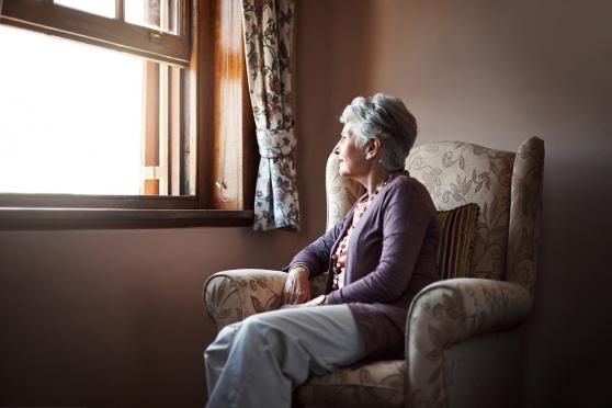 A senior woman looks out of a window